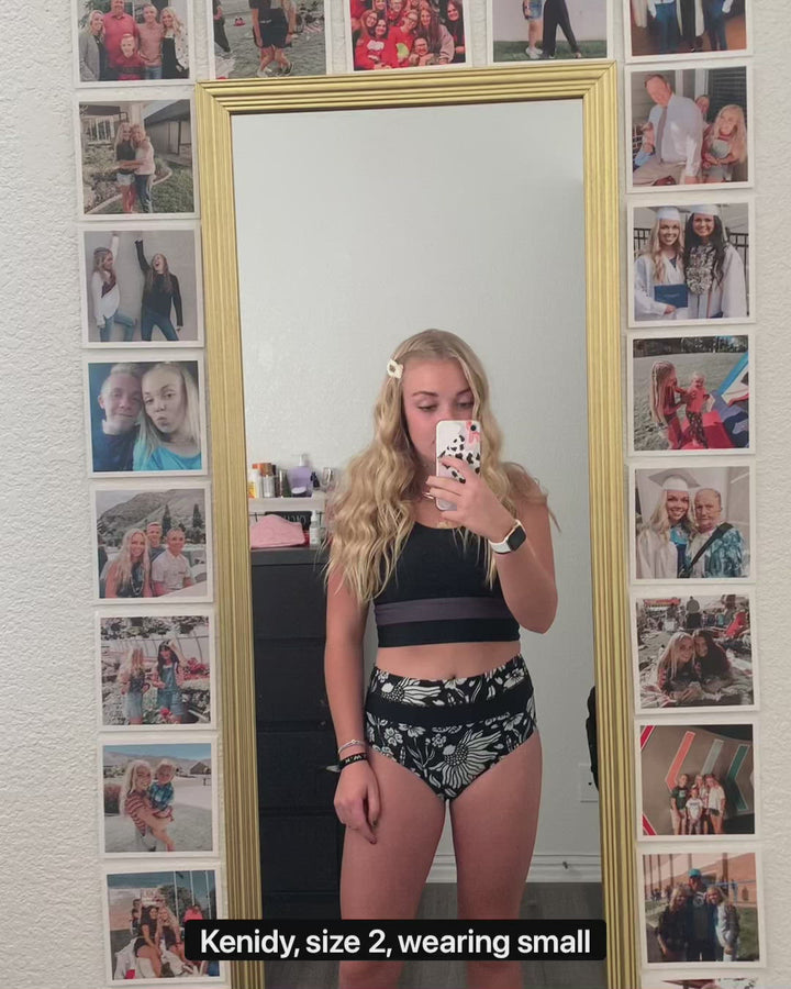 Video of a young women talking about how a black and white floral patterned swimsuit fits her.