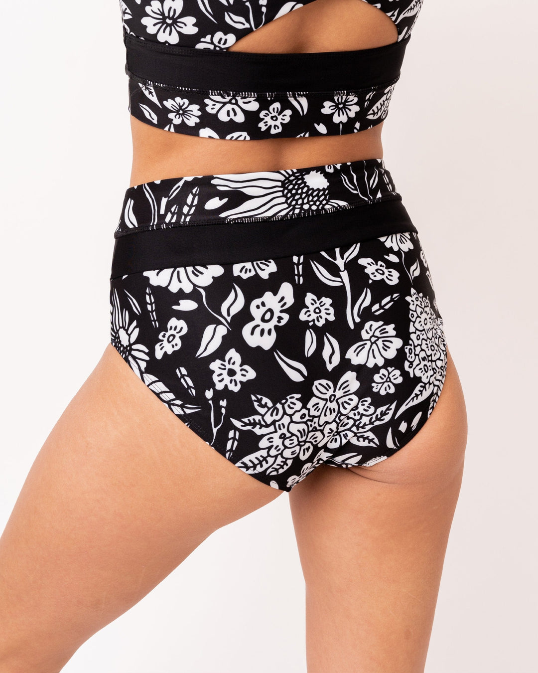 Back view studio image of black and white floral patterned swimsuit bottoms.
