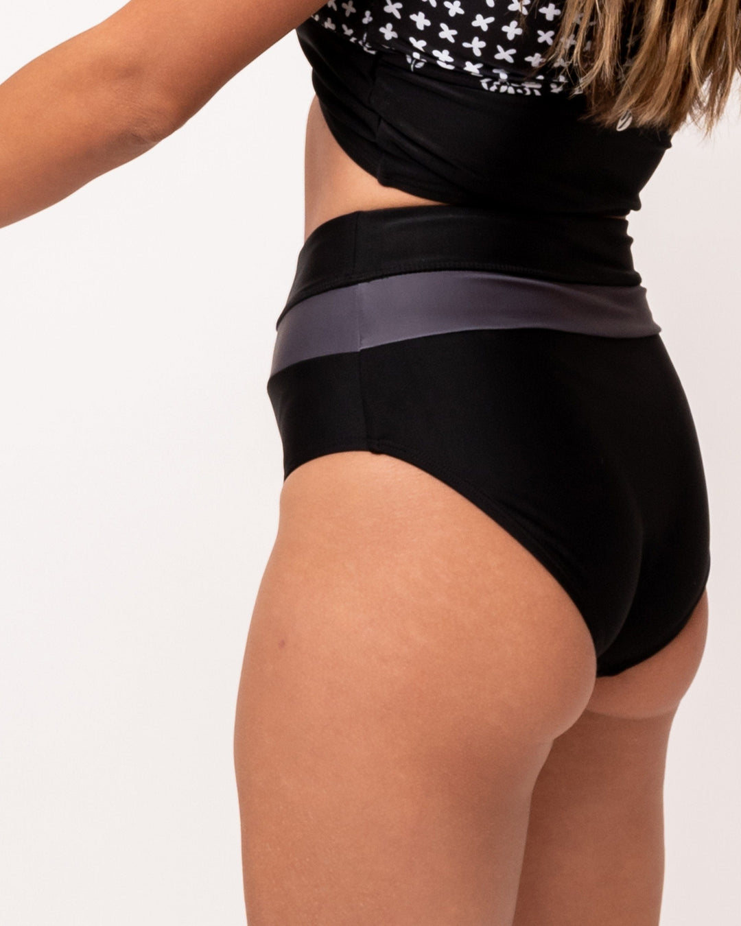 A studio image of a women wearing black and grey color blocked swimsuit bottoms.