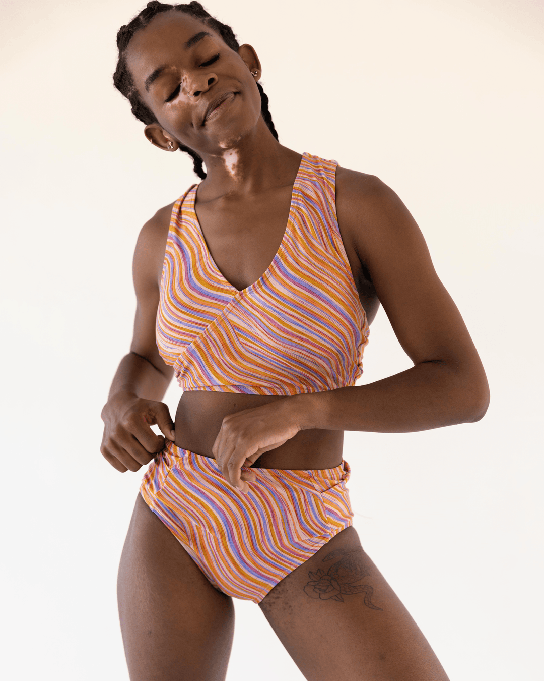 Front View studio picture of a girl wearing a retro pink, blue, purple and orange wave Yoga Pocket Bottom