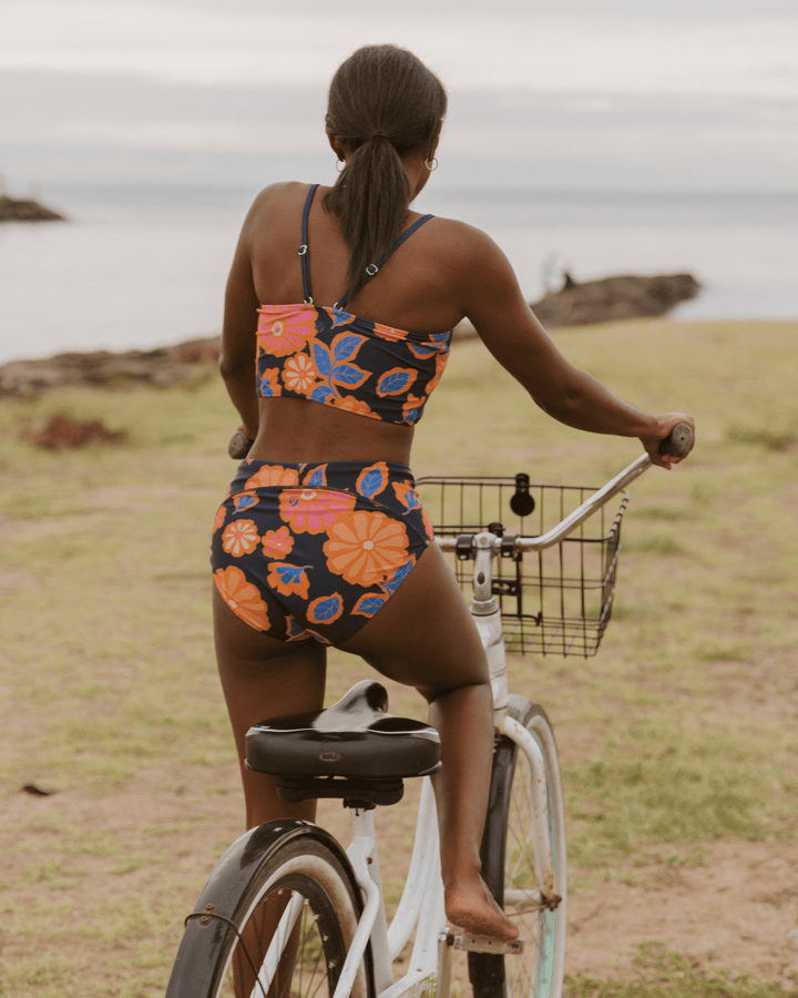 Woman riding her bike to the beach in Hawaii wearing a floral bikini set.