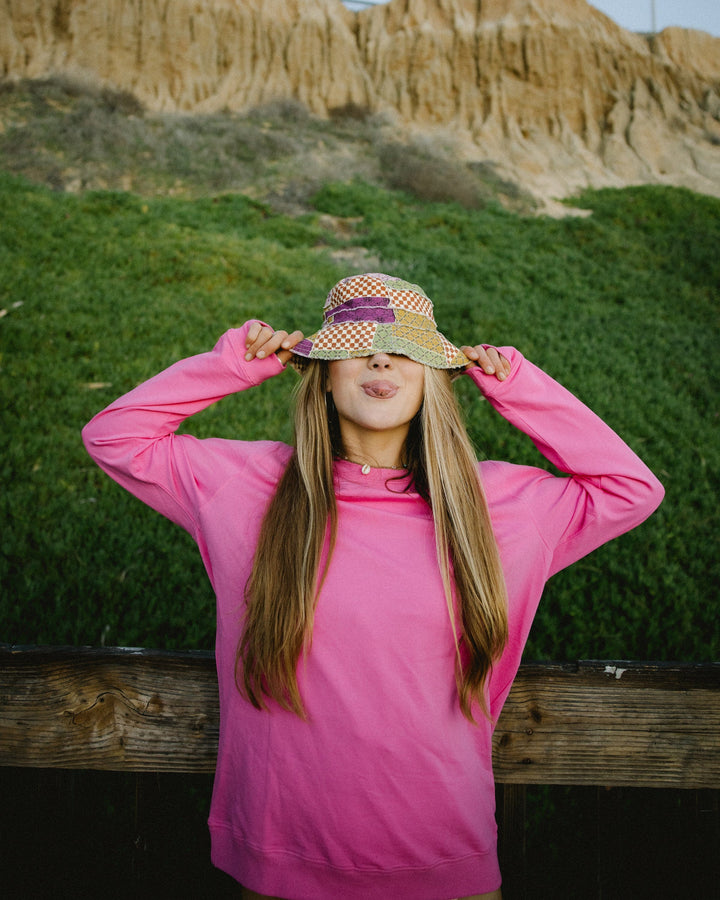 A women sticking her tongue out in a hot pink crewneck sweatshirt.