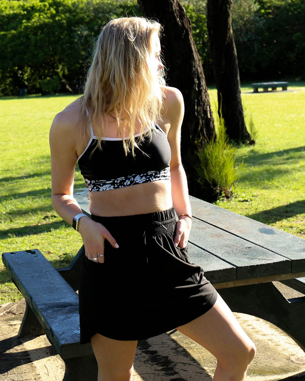 A women at a picnic table wearing a black athletic skirt.