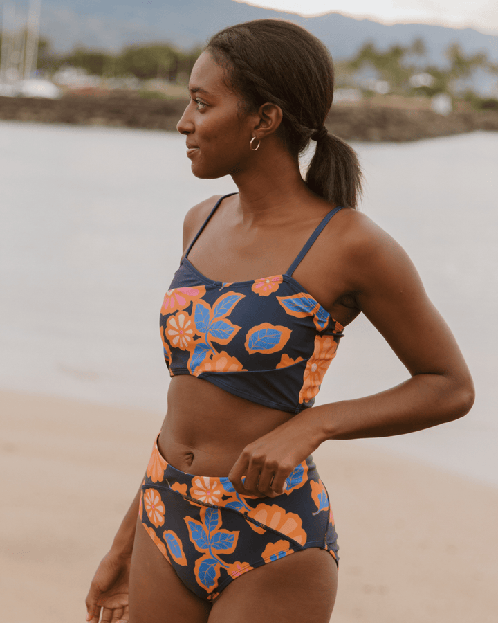 Girl wearing a floral bikini top and floral bikini bottoms on the beach.