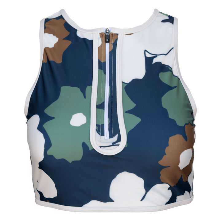 Floral patterned swim crop with a zipper and the floral pattern has ivory, green, navy, and brown floral print on a white background.